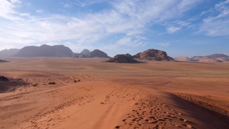 Panoramic-landscape-view-of-hostile,-barren-red-sandy-desert-and-mountainous-terrain-of-Arabian-Wadi-Rum-in-Jordan,-Middle-East