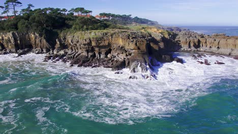 Aerial-view-of-the-waves-crashing-on-the-rocky-cliff-in-Cantabria,-Spain-during-a-sunny-day
