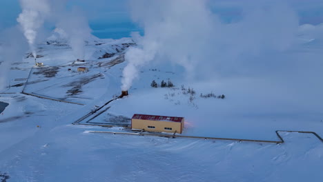 Weißer-Rauch-Kommt-Abends-Aus-Den-Geothermischen-Anlagen-In-Einer-Weißen-Verschneiten-Landschaft-In-Island