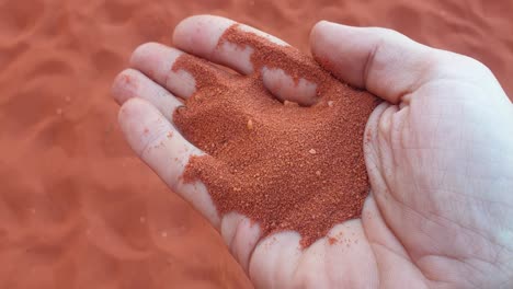 Red-sand-of-Wadi-Rum-desert-running-through-fingers,-close-up-of-a-handful-of-sand-in-Jordan,-Middle-East