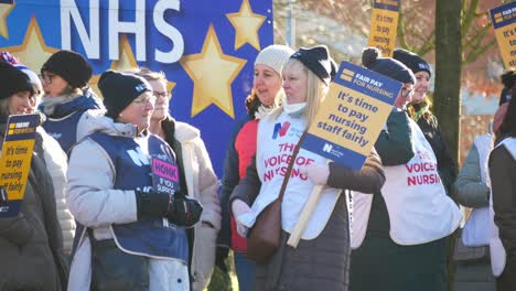 NHS-nurses-strike-dispute-for-fair-pay,-waving-banners-and-flags-outside-UK-hospital