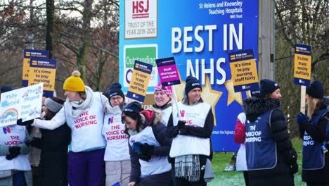 NHS-nurses-strike-for-fair-pay,-waving-banners-and-flags-outside-UK-hospital-in-the-cold