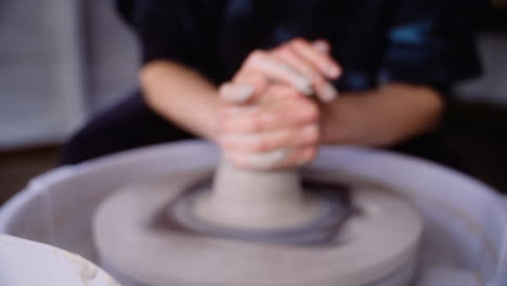 Potter-shapes-clay-into-a-pot-on-pottery-wheel-and-dips-hand-in-water