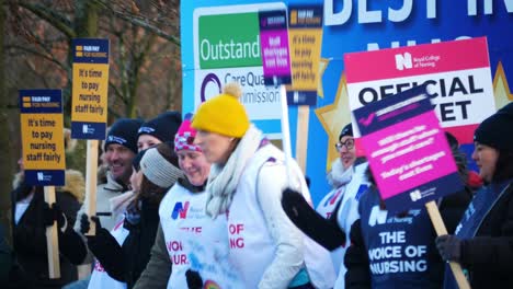 NHS-nurses-strike-for-fair-pay,-Chanting,-waving-banners-and-flags-outside-UK-hospital