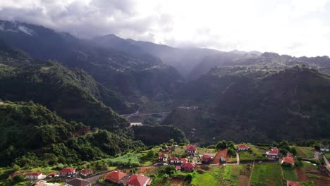 Aerial-reveal-of-villa-village-neighborhood-in-a-lush-green-landscape-with-mountain-in-background