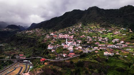 Aerial-landscape-of-a-town-on-green-volcanic-mountain-slope,-Madeira