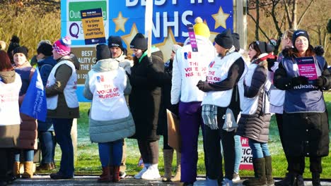 UK-hospital-nurses-protest-for-fair-pay,-holding-banners-and-waving-flags-on-strike