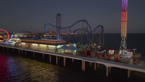 Drone-shot-close-to-amusement-park-rides-at-the-Galveston-Island-Historic-Pleasure-Pier,-dusk-in-Texas,-USA