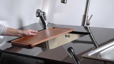 Kitchen-worktop-with-wood-cut-out-and-metal-tap-in-steel-kitchen