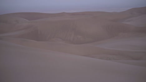 Panning-up-to-twilight-moon-looming-over-sand-dune-field