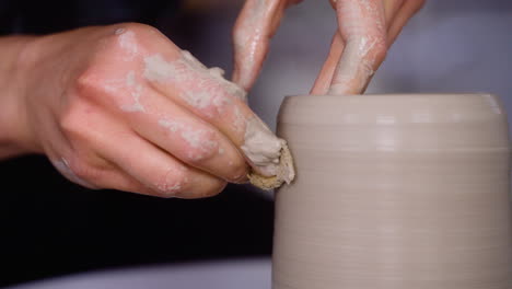 Potter-uses-sponge-to-shape-clay-pot-on-her-pottery-wheel