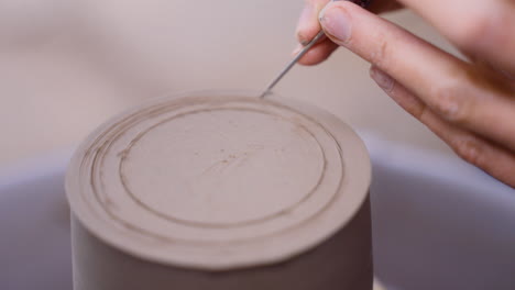Potter-scores-clay-on-pottery-wheel-from-two-different-angles