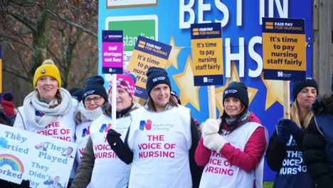 NHS-nurses-strike-for-fair-staff-pay,-waving-banners-and-flags-outside-UK-hospital