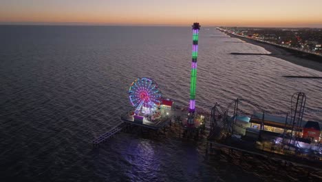 Colorful-evening-lights-at-the-Galveston-Island-Historic-Pleasure-Pier---Aerial-view