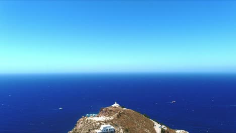Vista-Aérea-4k-Azul-Mar-Y-Cielo-Sobre-El-Faro-Akrotiri-En-La-Ladera-Escénica-En-Santorini-Grecia