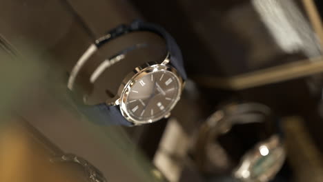 VERTICAL-Close-up-expensive-stylish-watches-rotating-behind-glass-jewellery-store-display