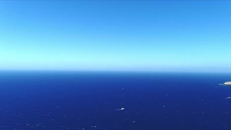 Aerial-4K-Blue-Sea-and-Sky-Top-View-Over-Akrotiri-Santorini-Greece-near-Boat-in-Ocean