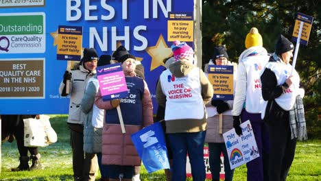 UK-hospital-nurses-union-protest-for-fair-pay,-holding-banners-and-flags-on-strike
