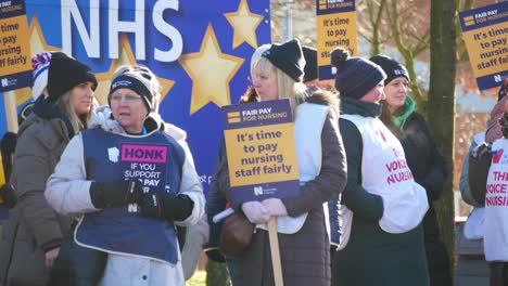 NHS-nurses-strike-for-fair-pay,-waving-banners-and-flags-outside-UK-St-Helens-hospital