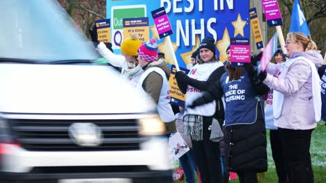 UK-hospital-nurses-protest-for-fair-pay,-holding-banners-and-flags-on-strike-demonstration