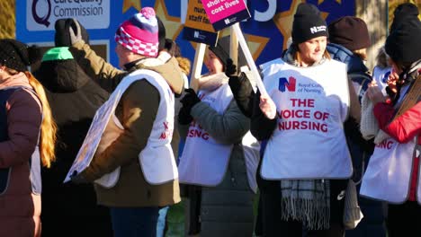 NHS-nurses-strike-for-fair-pay-and-better-healthcare-outside-St-Helens-hospital-on-a-chilly-winter-morning,-waving-banners-and-flags