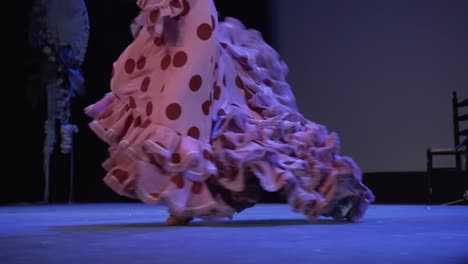Flamenco-dancer-heels-hard-and-moves-the-tail-of-pink-dress-with-red-polka-dots-on-stage