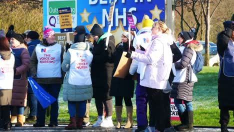 UK-hospital-nurses-protest-for-fair-pay,-holding-banners-and-flags-on-strike-unity
