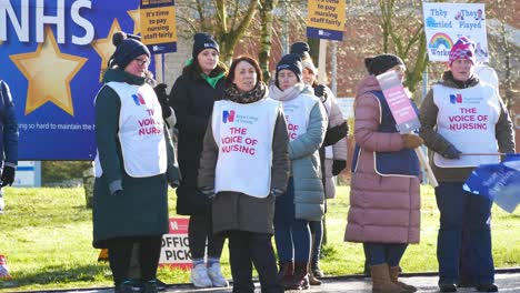 NHS-nurses-strike-for-fair-pay,-waving-banners-and-flags-outside-UK-hospital