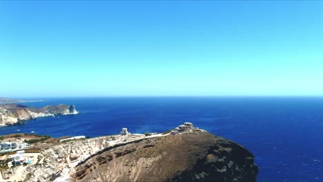 Luft-4k-Blaues-Meer-Und-Himmel-Draufsicht-über-Die-Dorfklippen-Von-Akra-Mavro-Vouno-Mit-Segelbooten,-Die-In-Der-Ferne-In-Santorini-Griechenland-Angedockt-Sind