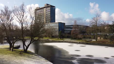 Aerial-view-Pilkington's-glass-head-office,-frosty-lake-and-gardens,-blue-high-rise-with-shared-office-space