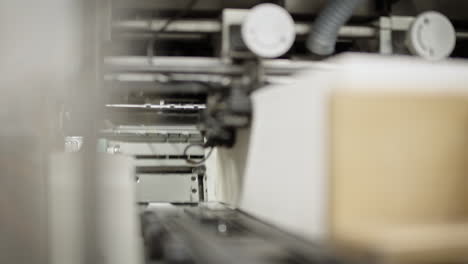 Close-up-shot-of-inside-of-a-printing-machine,-closing-and-opening,-paper-fast-traveling-past-the-opening