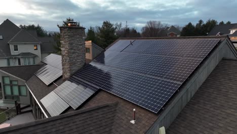 Aerial-orbit-reveal-of-sun-shining-on-solar-panels-on-large,-luxurious-home-in-America