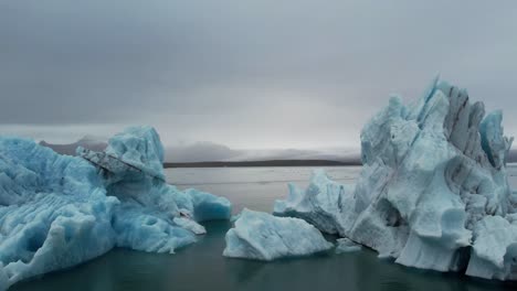 Filmischer-Flug-Zwischen-2-Massiven-Eisbergen-In-Island-An-Einem-Bewölkten-Tag