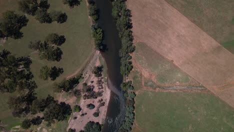Flowing-river-through-farmland-aerial-looking-straight-down,-Thornton
