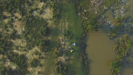 top-down-aerial-drone-shot-of-camping-tents-near-a-river-in-india