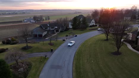 Aerial-approach-of-high-end-Audi-sedan-driving-in-upscale-residential-neighborhood-during-winter-sunset