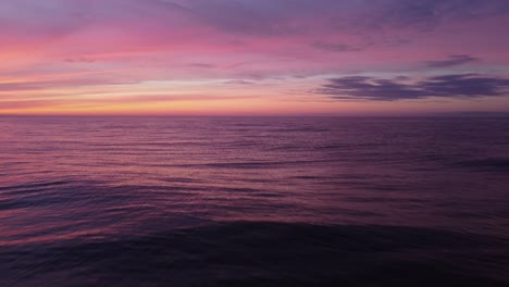 Violetter-Sonnenuntergang,-Der-Sich-In-Meereswellen-Widerspiegelt,-Antennenneigung-Bis-Nahe-An-Die-Wasseroberfläche