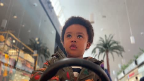 Two-year-old-black-baby,-mix-raced,-driving-an-electric-toy-car-inside-a-Mall