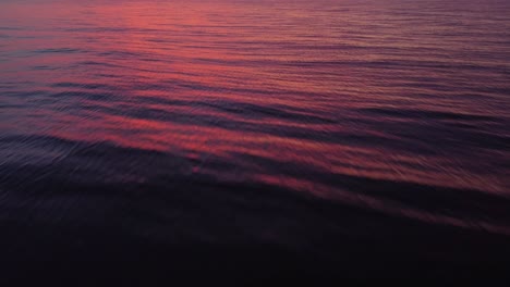 Water-surface-reflecting-colorful-sunset,-tilt-up-towards-sky