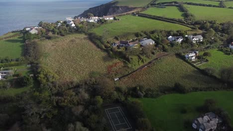 Aerial-drone-tracking-shot-of-a-land-rover-4x4-travelling-through-an-English-village-in-the-countryside-with-a-rocky-coastline---Lee-Bay,-Beach,-Ilfracombe,-Devon,-England