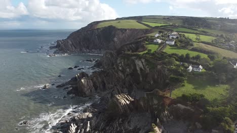 Aerial-drone-tracking-shot-of-houses-sitting-on-top-of-a-rocky-cliff-face---Lee-Bay,-Beach,-Ilfracombe,-Devon,-England