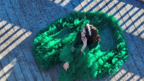 Women-sitting-outdoors-with-a-green-dress-posing-for-a-photographer