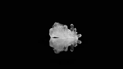 Crystal-clear-quartz-glistening-under-studio-lighting-on-black-background,-captured-through-smooth-zoom-in-dolly