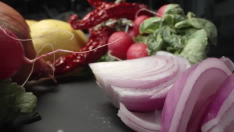 A-probe-macro-lens-captures-radishes,-peppers,-purple-onion-and-lemons-on-a-rustic-wood-table