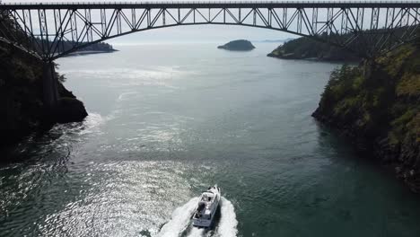 Cinematic-drone-shot-fly-under-following-a-boat-in-deception-pass-bridge-in-anacortes-washington-WA-USA-on-a-sunny-spring-day