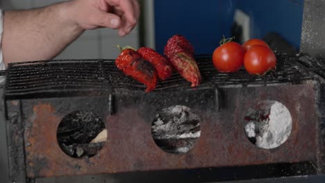 Cook-puts-tomatoes-and-peppers-on-charcoal-fire-grill-to-prepare-healthy-Mediterranean-cuisine