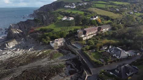 Aerial-drone-orbit-of-an-English-seaside-village-in-the-countryside-with-a-rocky-beach-in-a-valley---Lee-Bay,-Beach,-Ilfracombe,-Devon
