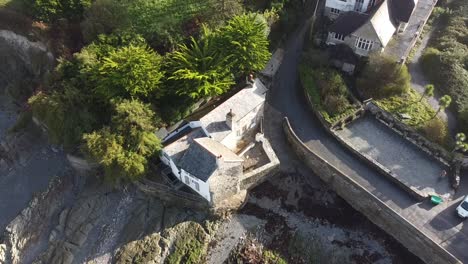 Aerial-drone-tilt-shot-of-an-English-mill-house-on-the-shoreline-of-a-coastal-village---Lee-Bay,-Beach,-Ilfracombe,-Devon,-England