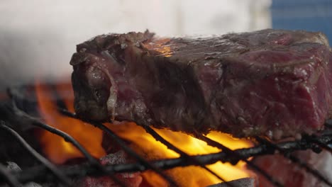 Close-up-of-grilled-fillet-steak-between-flames-and-embers-of-barbecue-charcoal
