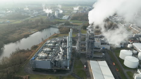 Smoke-and-steam-rising-of-an-industrial-facility,-CO2-emissions,-air-pollution,-exhaust-gases,-aerial
